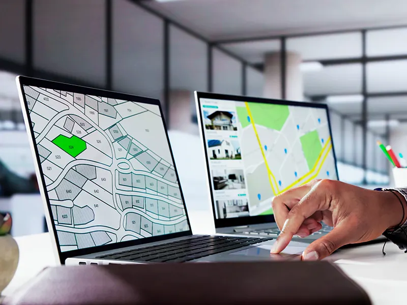 GIS Data Analysis and Layer Mapping for Planning Person working on GIS data analysis with maps and layers displayed on laptop screens for planning and digitizing features.